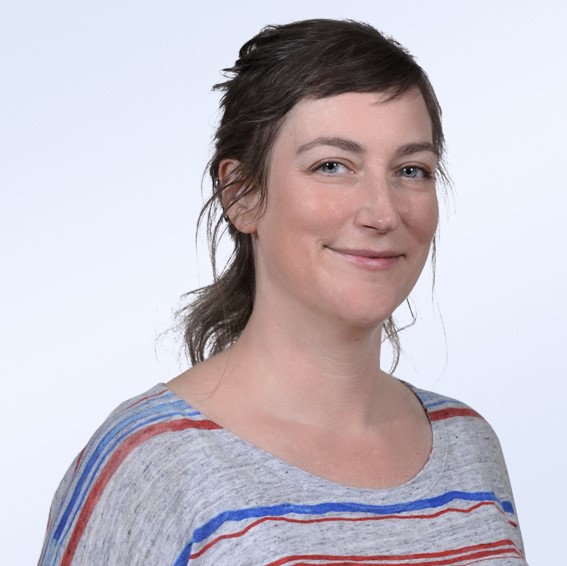 Profilbild von Julia Hein in einem grauen Pullover mit roten und blauen Streifen.