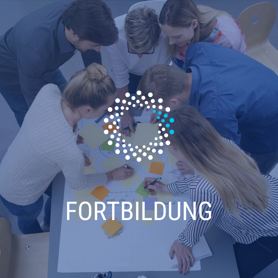 Fortbildung (Sechs Personen sind stehend über einen kleinen Tisch gebeugt, auf dem sich ein großes Flipchartpapier sowie zahlreiche bunte Post-Its befinden, die sie gerade beschriften.)
